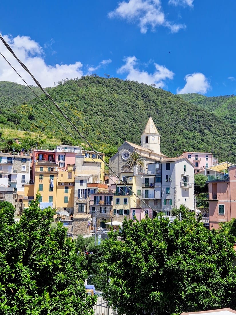 Corniglia - Kohti avaraa maailmaaKuluneet ovet, joiden maalipinta hilseili kauniisti, rapistuneet ikkunaluukut ja kiviseinät, joihin oli kiinnitetty kukkaruukku jos toinenkin. Köynnökset kiersivät kaiteita ja vanhoja putkia, ja jokaisessa pihassa kasvoi jotakin vihreää — oli se sitten ruukussa, raoissa tai aidan vieressä. Cornigliassa on jotain taianomaista: täällä aika ei tunnu pysähtyneeltä, vaan se vain virtaa hitaammin. Rakennusten rujous ja kasvien vehreys täydentävät toisiaan niin, että niistä syntyy oma satumaailmansa. Tuntuu, että jokainen ovi, portaikko ja ruukku haluaa tulla kuvatuksi, kuin ne olisivat osa kylän yhteistä tarinaa.